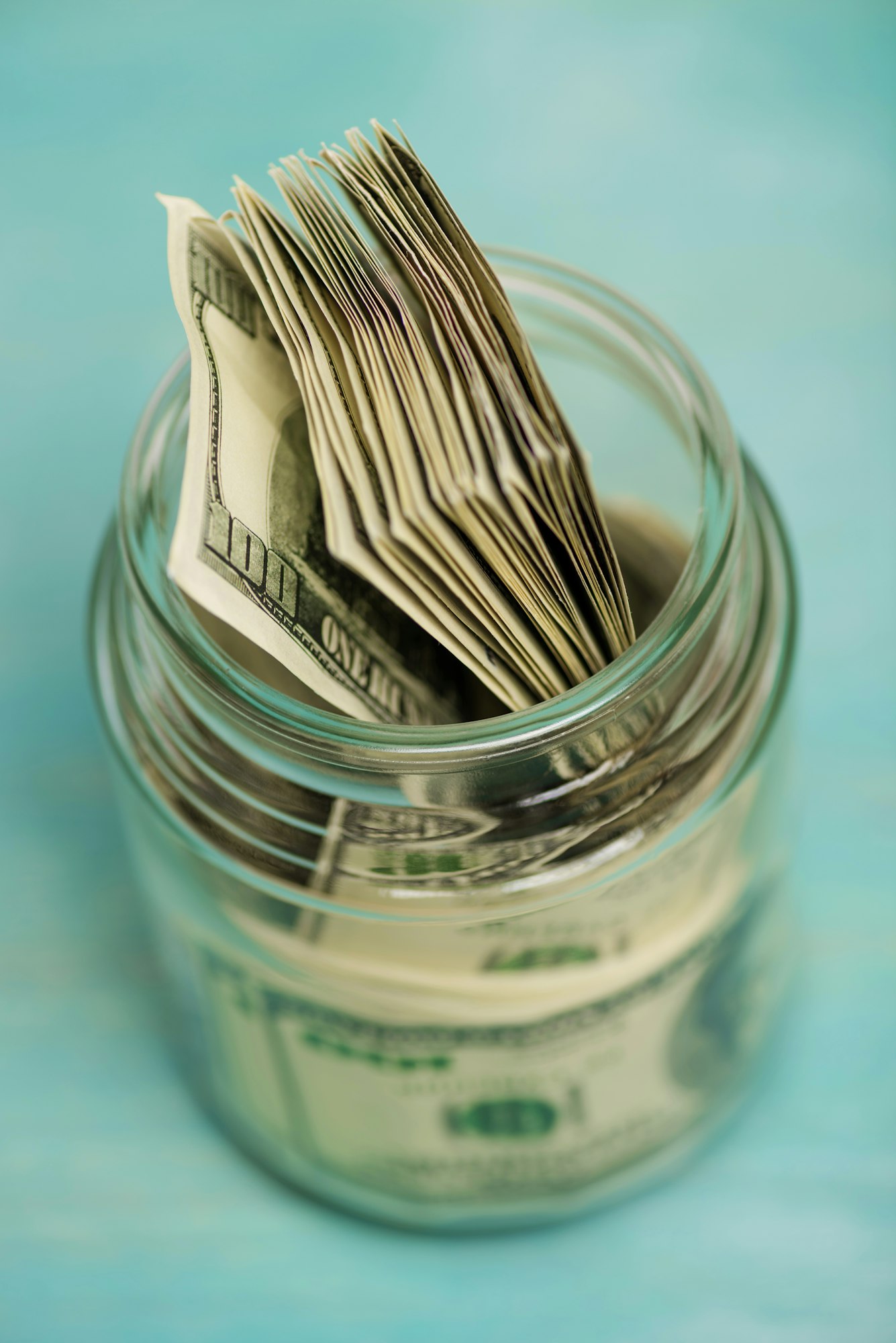 Close-up high angle view of dollar banknotes in glass jar, donation concept